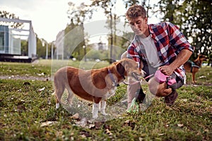 A young guy in the park is cleaning up after her dog. Friendship, walk, pets