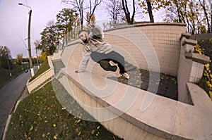 A young guy performs a jump through the concrete parapet