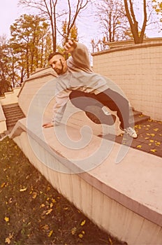 A young guy performs a jump through the concrete parapet