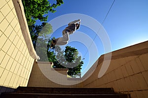 A young guy performs a jump through the space between the concrete parapets