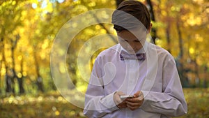 Young guy playing in the phone and walking in the autumn park.