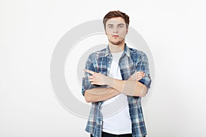 Young guy pointing copy space isolated on white background. Handsome young smiling man in shirt looking at camera and pointing
