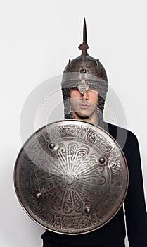 Young guy is posing in studio with helmet and shield. Knight, halloween concept.