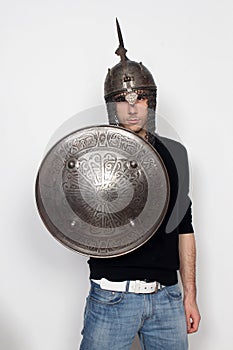 Young guy is posing in studio with helmet and shield. Knight, halloween concept.