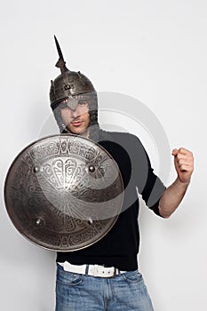 Young guy is posing in studio with helmet and shield. Knight, halloween concept.