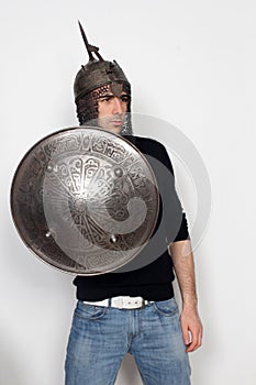 Young guy is posing in studio with helmet and shield. Knight, halloween concept.