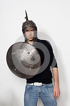 Young guy is posing in studio with helmet and shield. Knight, halloween concept.