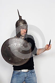 Young guy is posing in studio with helmet and shield. Knight, halloween concept.