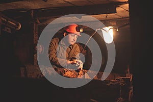 A young guy in a protective suit and helmet sits in a tunnel with a burning scrapbook