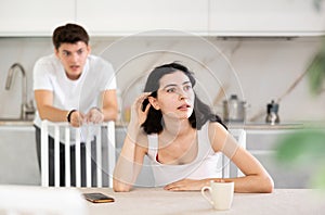 Young guy quarrels with young woman in kitchen