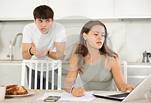 Young guy quarrels with young woman working at laptop