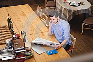 Young guy read a newspaper and talking by phone in the Italian s