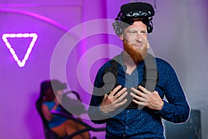 A young guy, with a red beard, is playing virtual reality games