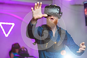 A young guy, with a red beard, is playing virtual reality games
