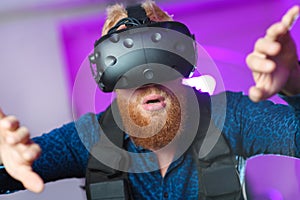 A young guy, with a red beard, is playing virtual reality games