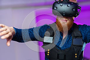 A young guy, with a red beard, is playing virtual reality games