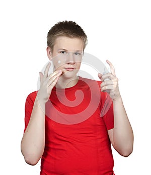 The young guy in a red t-shirt to put cosmetic cream on a face.Portrait on a white background