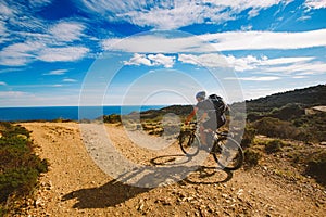 A young guy riding a mountain bike on a bicycle route in Spain on road against the background of the Mediterranean Sea