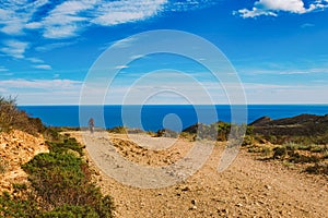 A young guy riding a mountain bike on a bicycle route in Spain on road against the background of the Mediterranean Sea