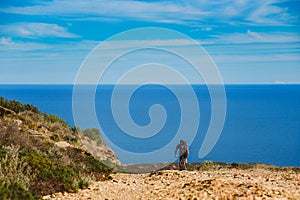 A young guy riding a mountain bike on a bicycle route in Spain on road against the background of the Mediterranean Sea. Dressed in