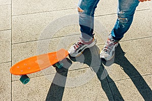 Young guy in ripped jeans standing with penny board in the park. summer activities skateboarding