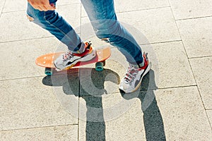 Young guy in ripped jeans standing with penny board in the park. summer activities skateboarding