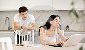 Young guy quarrels with young woman working at laptop