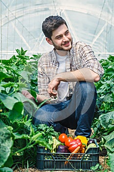 Young guy is sitting between rows of plants.
