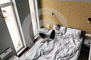 Young guy sleeping on comfy bed in modern hotel room