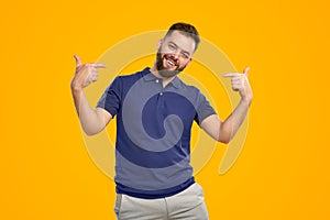 Young guy smiling at camera and pointing self in studio photo