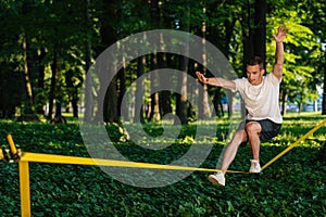 Young guy in sportwear walking on the rope and looking focused