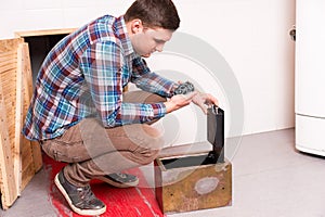 Young guy squatting and opened the safe looks at the puzzle trying to get out of the kitchen with a bloody floor