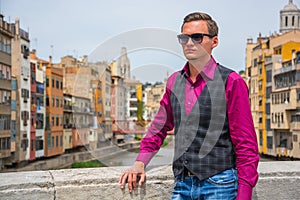 A young guy stands near the river Onyar in Girona, Spain