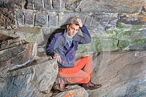 A young guy is stressfully fitting in a corner of rocks