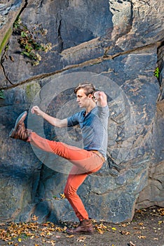 A young guy is stretching legs, walking robot likely by rocks