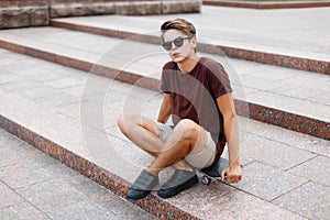 Young guy in a T-shirt with sunglasses and shorts sitting