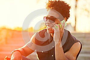 Young guy is talking on phone at sunset background.