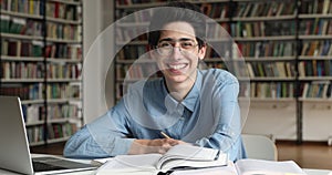 Young guy teenage high schooler posing at library work desk