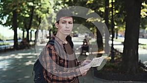 Young guy tourist holds a paper map in his hands and tries to navigate the terrain