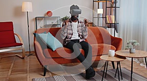 Young guy use virtual reality headset glasses at home play 3D video game making gestures with hands