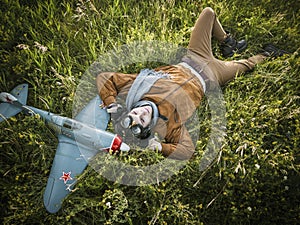 Young guy in vintage clothes pilot with an airplane model outdoors