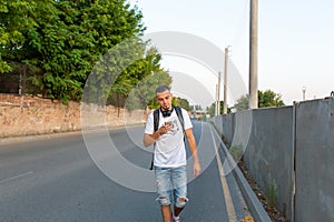 A young guy walks down the street looking at the phone