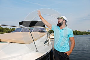 A young guy waves his hand to someone near the yacht