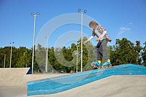 Young guy wearing inline skates doing balancing stunt at skateboard park