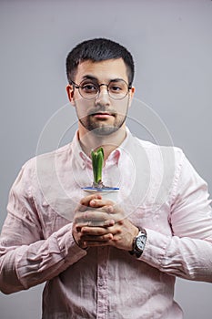 A young guy in white shirt holding a flower in a pot