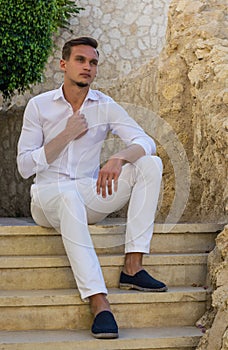 Young guy in a white shirt sits on the stairs