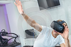 A young guy in a white T-shirt plays virtual reality games