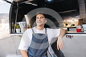 Young guy working as a chef in a food truck standing with closed eyes and smiling