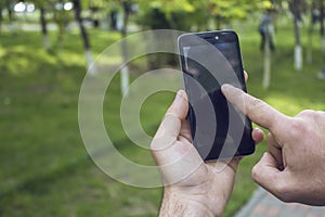 Young guy works with phone in park