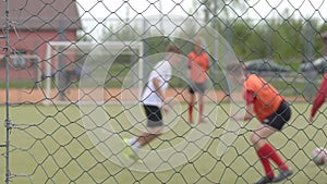 Young guys playing football in the stadium behind bars, background, copy space, slow motion